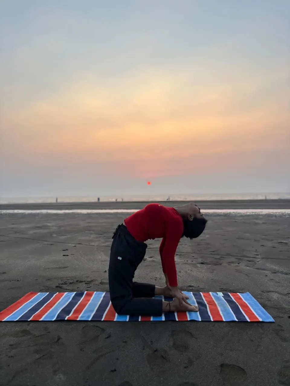Neha in camel pose on the beach as the sun sets