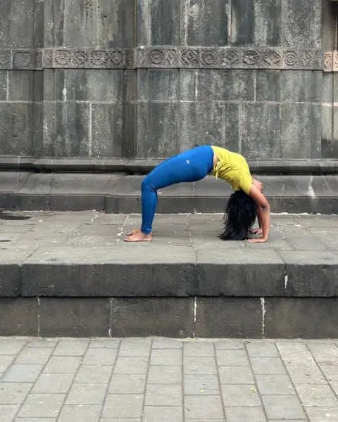 Neha in wheel pose on the steps of a stone temple